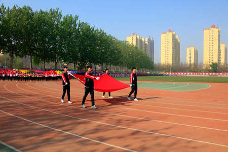 Luannan County - April 21, 2016: flag hand walking on the playground, Luannan County, Hebei Province, Chinaのeditorial素材
