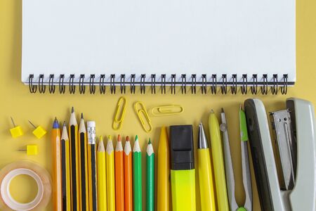 Back to school concept. Open empty mockup notebook and colored school stationery. Yellow paper background.の写真素材