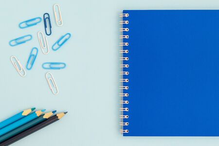 back to school creative concept. blue notebook with pencils and clips on a blue background top view of a flat lay. boyish or male school toolsの写真素材