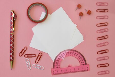Back to school concept. Paper for writing with pencils, clips and tape on a pink background.の写真素材