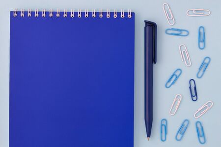 back to school creative concept. blue notebook with pen and paper clips on a blue background top view of a flat lay.の写真素材