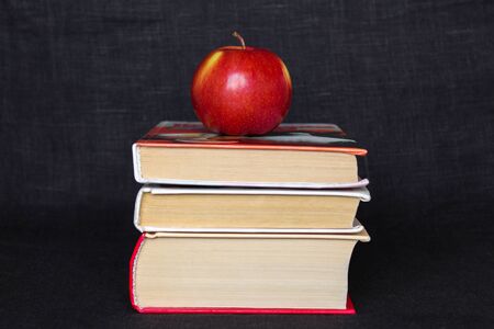 Pile stack of books with red apple on top, back to school concept, education teacher concept, horizontal shot copy text space, black backgroundの写真素材