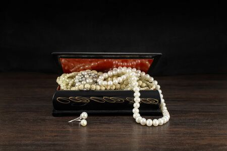 Pearls in old jewelry open chest, vintage treasure box and pearl necklaces. Mysterious golden light inside. Design concept. Picture for wallpaper.の写真素材