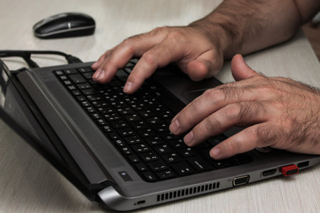 A man works on a laptop. Mens hands are typing on a laptop closeup. Business concept, office concept