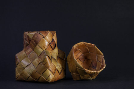 Wicker basket of birch bark on a black background. Basket with place for text. Russian traditions...