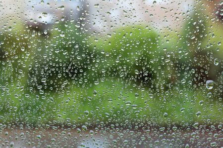 Raindrops on the window. Drops of water or rain drops on window glass with blur buildings background.の写真素材