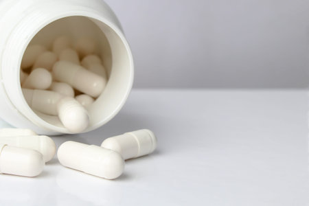 White pills from a white jar on a light background. Professionally photo with place for text
