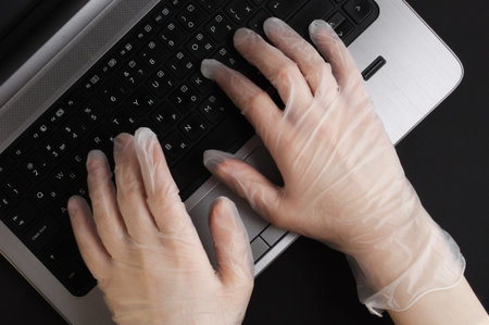 Woman in gloves working on laptop. Working from home. Home office, Coronavirus