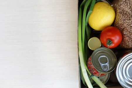 Food supplies crisis food stock for quarantine isolation period on light background. Canned food, buckwheat, lemon, tomato, green onion. Food delivery, Donation, coronavirus quarantine. Copyspace.の写真素材