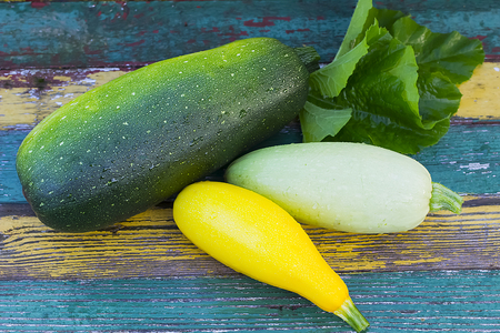 Yellow, green and white zucchini on a old wooden board.の写真素材