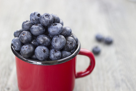 Bright ripe blueberry in a metal cup on a gray wooden background. Soft focus.の写真素材