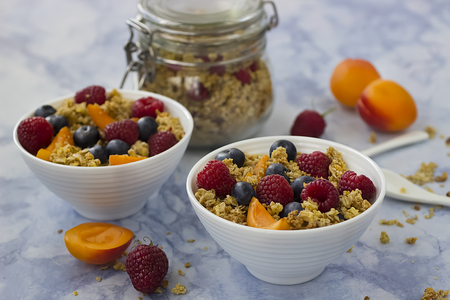 Bowls of granola with blueberries and fresh fruit on marble table.の写真素材