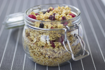 Bowls of  granola  with dry raspberries, cranberries and blueberries on marble table. Soft focus.の写真素材