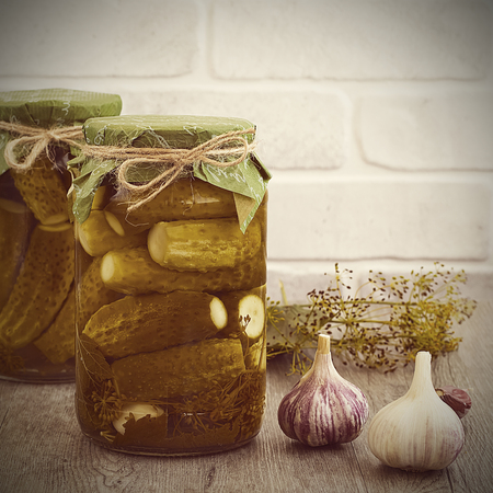 Pickled cucumbers in glass jar on a gray wooden table.の写真素材