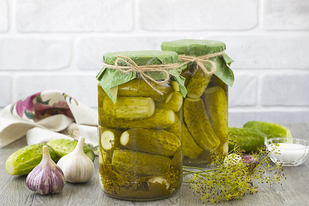 Pickled cucumbers in glass jar on a gray wooden table.の写真素材