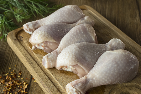 Fresh raw chicken legs on a cutting board on wooden table.  Horizontal. Soft focus.の写真素材