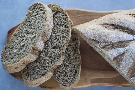 Multigrain bread on a wooden board on a gray background. Healthy eating concept. Soft focus.の写真素材
