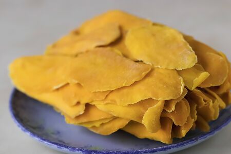 Sun-dried mango slices on a blue plate close-up. Soft focus.の写真素材