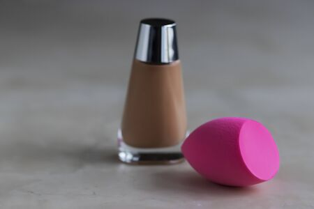 Pink cosmetic sponge and bottle with foundation on a light background. Soft focus.の写真素材