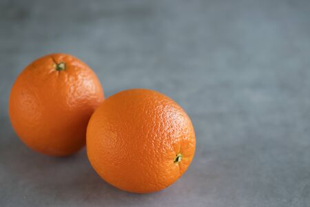 Two bright whole oranges on a gray background. Soft focus. Copy spaceの写真素材