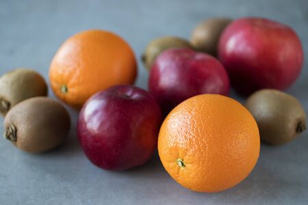 Fresh whole oranges, apples and kiwi on a gray background. Soft focus.の写真素材