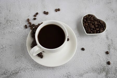 White cup with black coffee and coffee beans on a concrete. Soft focus.の写真素材