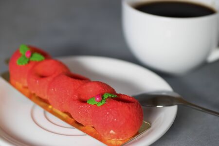 Red mousse cake and a white cup of espresso on a gray background.の写真素材