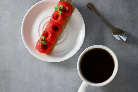 Red mousse cake and a white cup of espresso on a gray background. Top view.の写真素材
