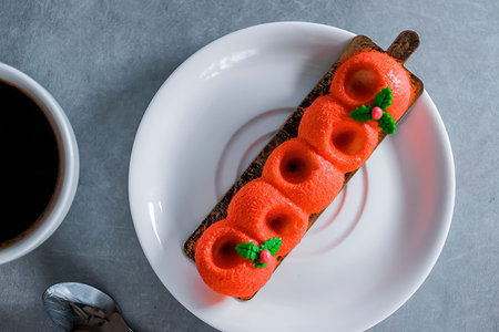 Red mousse cake and a white cup of espresso on a gray background.
