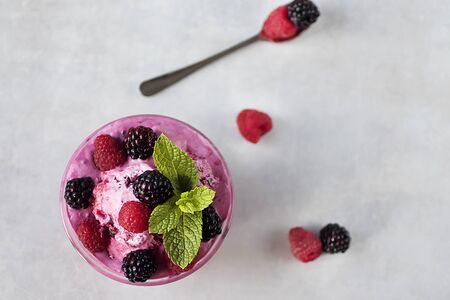 Homemade berry sorbet in glass cups, mint leaves and fresh berries on gray background. Soft focus.の写真素材