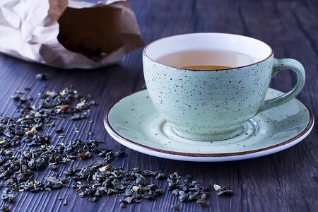 Cup of green tea and dry green tea on brown wooden background. Soft focus.の写真素材