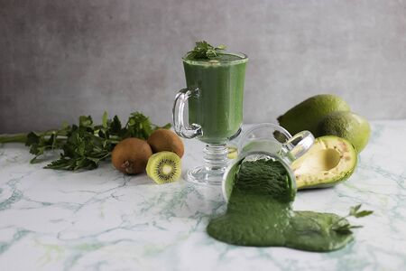 Green smoothie made from greens, kiwi, avocado, apple and spirulina in a glass cups. Superfood concept. Soft focus.の写真素材