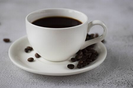 White cup with black coffee and coffee beans on a concrete background. Soft focus.の写真素材