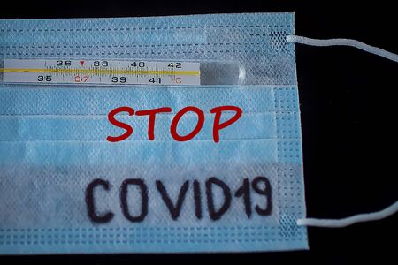Disposable medical mask and thermometer on a black background. Coronavirus  concept. COVID-19. Soft focus.の写真素材