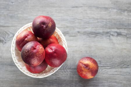 Fresh organic nectarines in a white basket on a gray wooden table. Top view. Soft focus.の写真素材