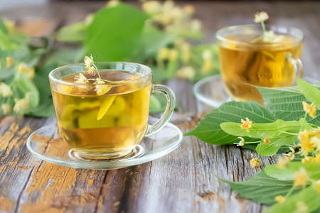 Herbal tea with linden inflorescences in glass cups on an old wooden table. Rustic style. Soft focus.の写真素材