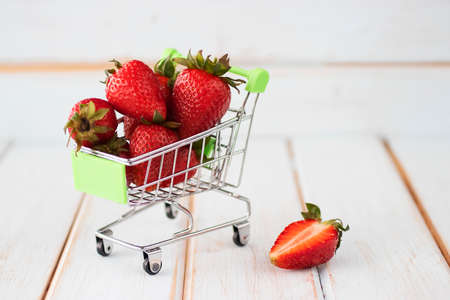 Fresh strawberries in a supermarket trolley on wooden background. Soft focus.の写真素材