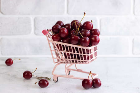 Fresh cherries in a supermarket trolley on a gray concrete background. Soft focus.の写真素材