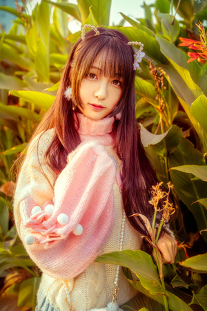 A young girl stood by the green leafの写真素材