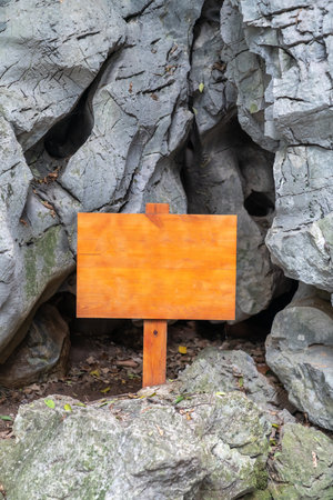 A blank wooden warning sign stood in the rocks of the mountainの写真素材
