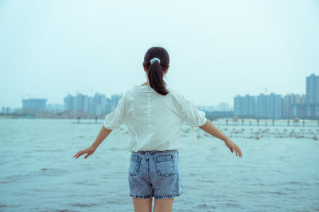 A girl dressed in white is standing by the lakeの写真素材