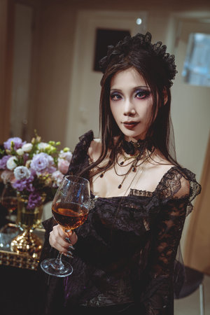 A young Chinese girl dressed in purple gothic attire posing elegantly indoorsの写真素材