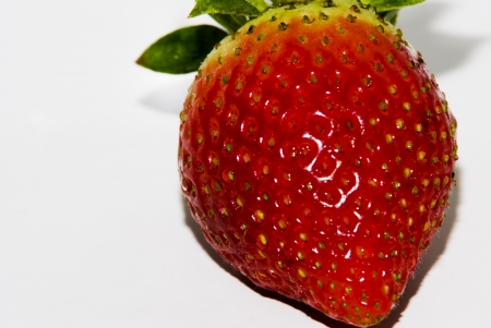 ripe red strawberry with green leaves on white backgroundの写真素材