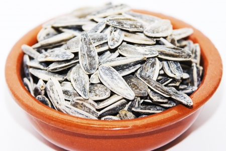 salted sunflower seeds in clay pot on white backgroundの写真素材