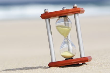 hourglass on the sandy beach with sea in the backgroundの写真素材