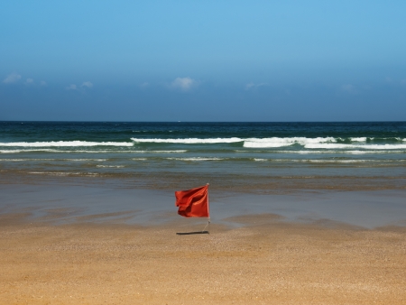 red flag on lonely beach in spainの写真素材
