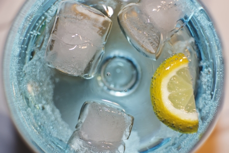 blue liqueur glass with ice cubes and lemonの写真素材