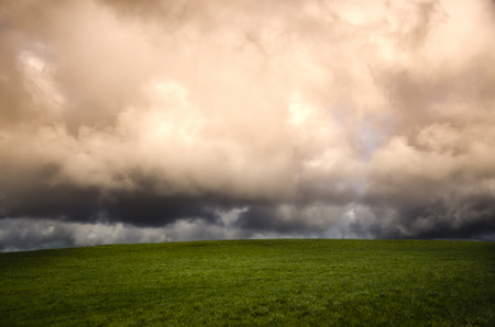 winter landscape with green field and storm cloudsの写真素材
