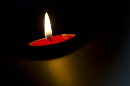 Red candle buning peacefully. Black background.の写真素材