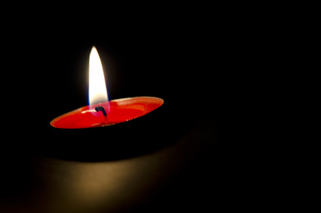 Red candle buning peacefully. Black background.の写真素材